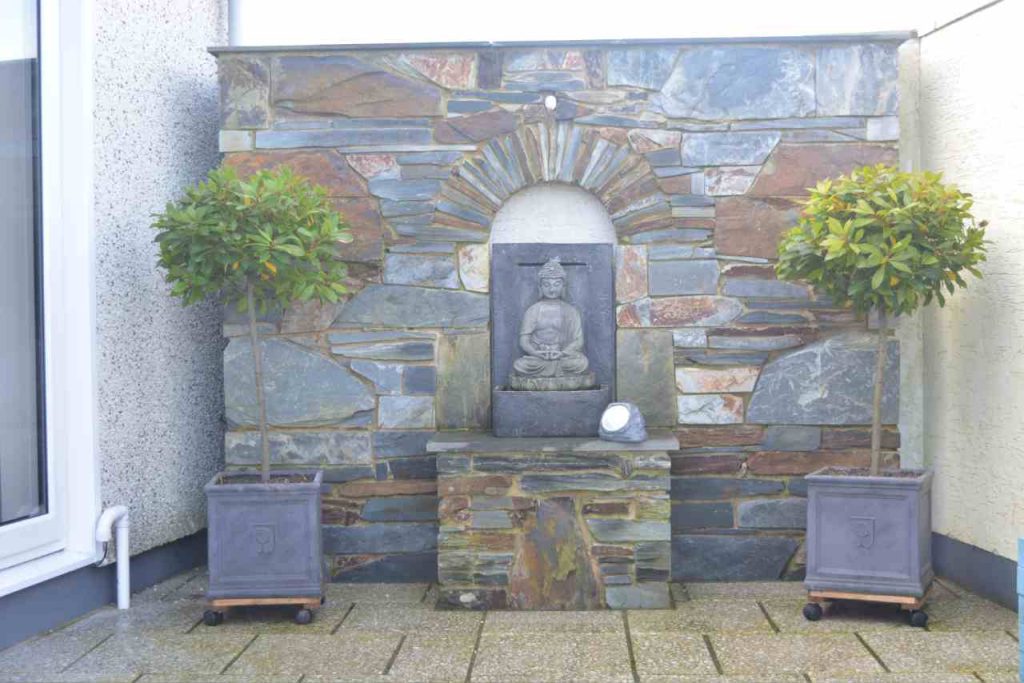 Cornish stone wall and plinth with arch and Buddha water feature and 2 x bay trees